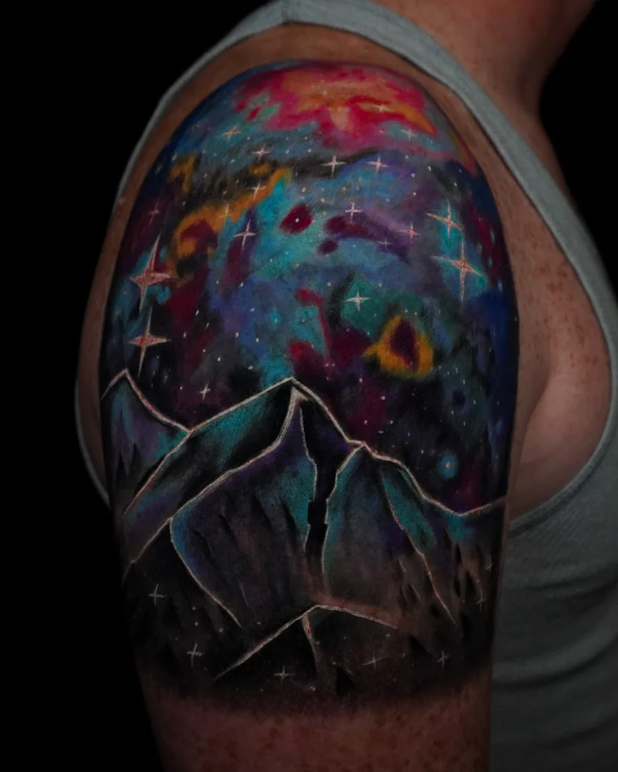 A colorful upper-arm landscape with dark mountain peaks beneath a luminous cosmic sky.