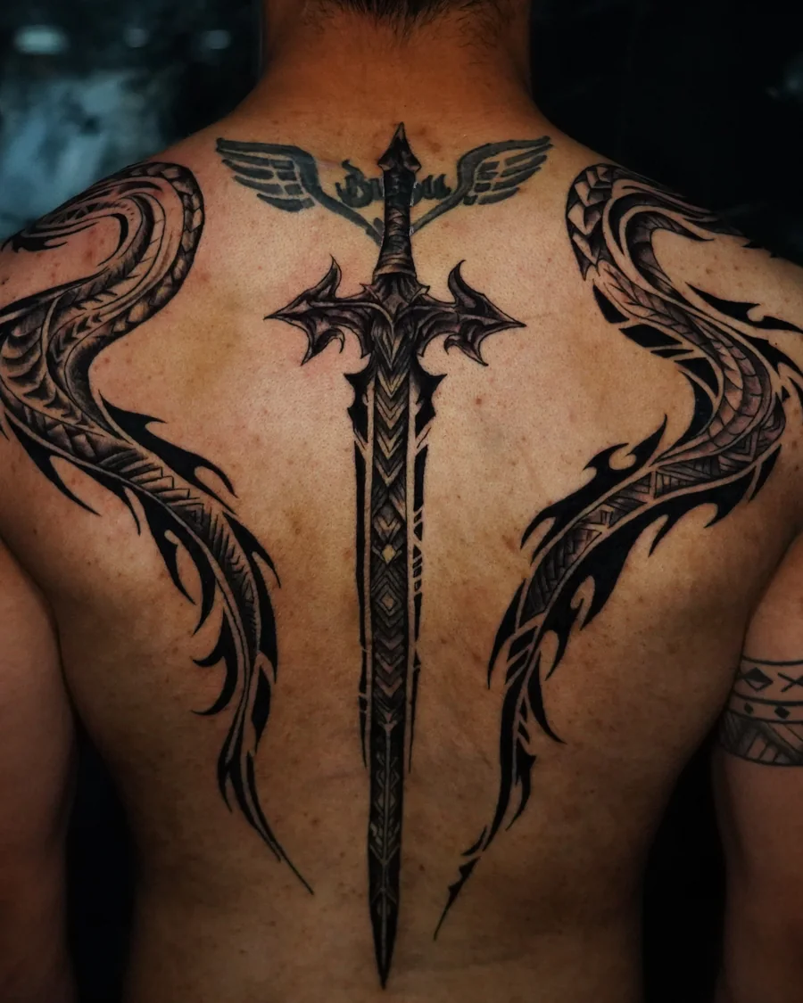 Blackwork dragon tattoos extending from the chest over both shoulders to the back, with their bodies curving beside a central sword tattoo.