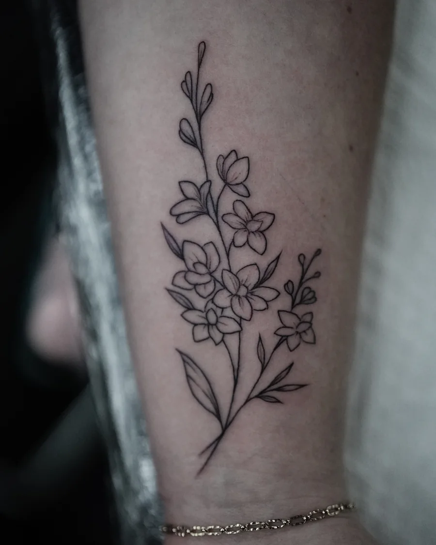 A delicate linework stem with small flowers, buds and leaves near the wrist.