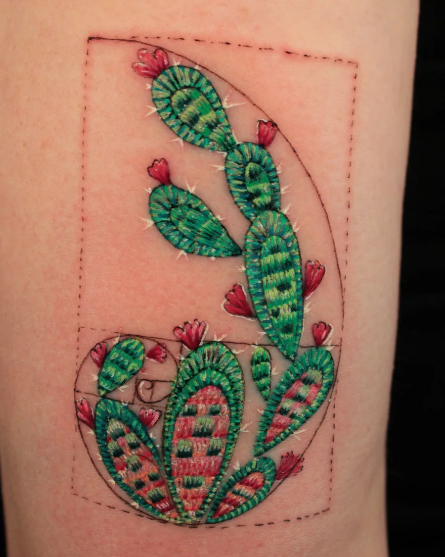 A green prickly pear cactus with pink flowers inside a red geometric frame.