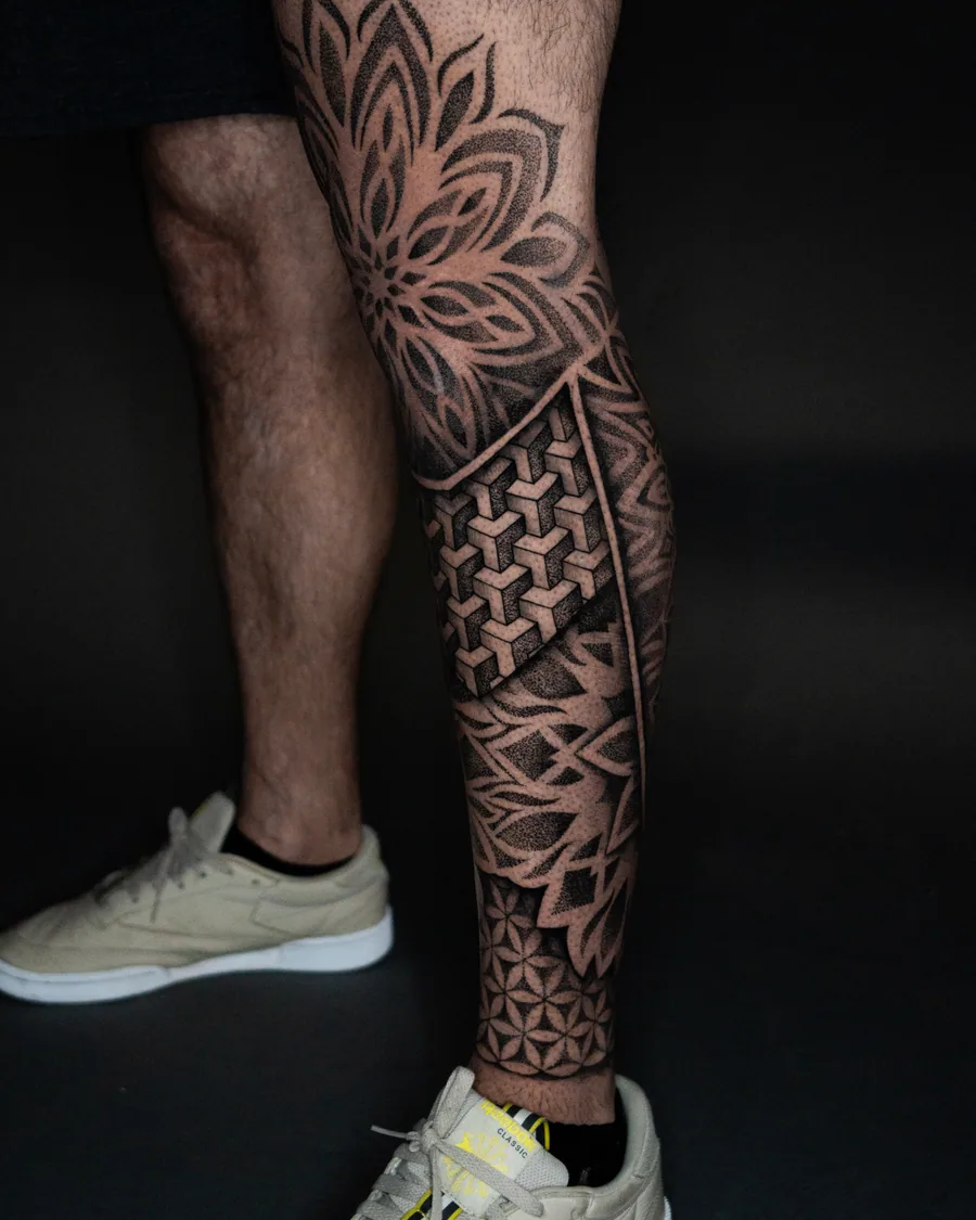 A black-and-gray geometric leg tattoo combining dotwork petals, interlocking cubes and repeating star patterns.
